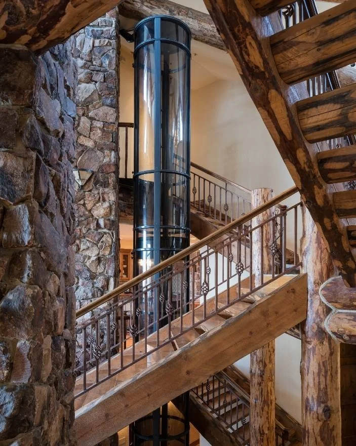 PVE vacuum elevator with black trim installed beside a rustic log staircase for Canada homes